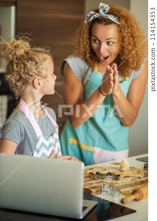 Child and women cutting form for cookie in dough. Happy family and childhood. 114154353