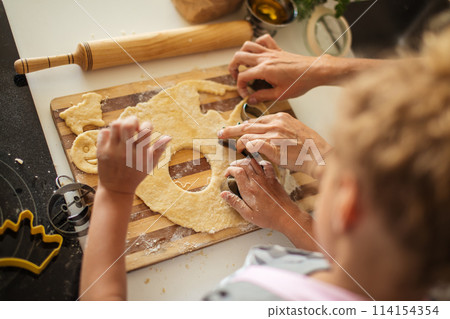 Child and women cutting form for cookie in dough. Happy family and childhood. Child and women cutting form for cookie in dough. Happy family and childhood. 114154354