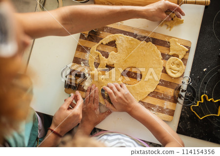 Child and women cutting form for cookie in dough. Happy family and childhood. 114154356