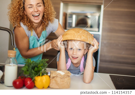 Mother and daughter having fun in the kitchen while preparing cookies. 114154357