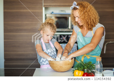 Mother and child daughter girl having fun while making dinner at the kitchen. 114154392