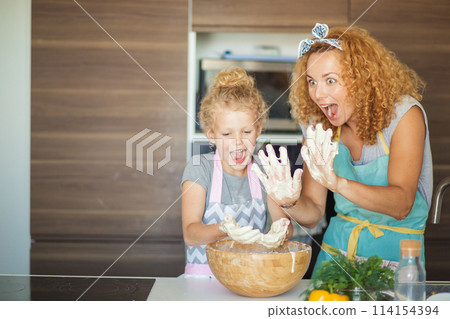 Mother and child daughter girl having fun while making dinner at the kitchen. 114154394