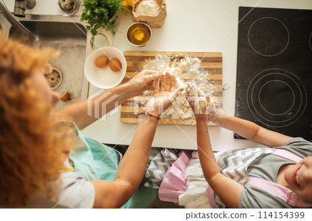 Top view of woman and little daughter making cookies while cooking on kitchen. 114154399