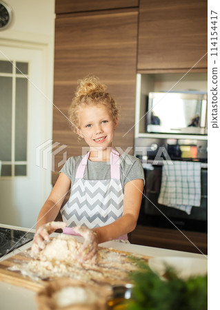 little girl kneading dough, baking cookies for christmas 114154417