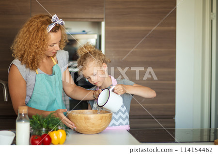 Little daughter helping mother baking in kitchen, family and cooking 114154462