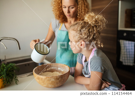 Little daughter helping mother baking in kitchen, family and cooking 114154464