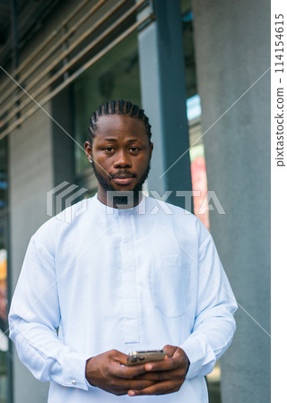 Cheerful male tourist portrait dress in white wear dashiki ethnic smiling at city street or small town background. African American travel model have free time. Millennial generation and gen z people 114154615