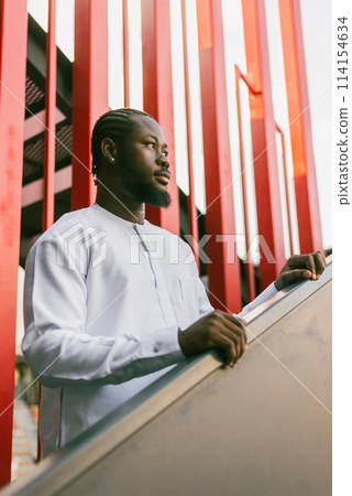 Close up portrait of a happy african american man smiling wearing ethnic dashiki clothes outdoor in summer street background. Millennial generation student and youth. Copy space Close up portrait of a happy african american man smiling wearing ethnic dashiki clothes outdoor in summer street background. Millennial generation student and youth. Copy space 114154634