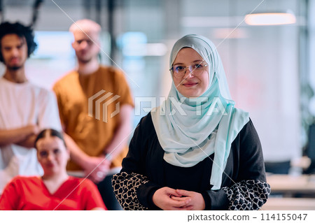 A diverse group of young business people walking a corridor in the glass-enclosed office of a modern startup, including a person in a wheelchair and a woman wearing a hijab A diverse group of young business people walking a corridor in the glass-enclosed office of a modern startup, including a person in a wheelchair and a woman wearing a hijab 114155047
