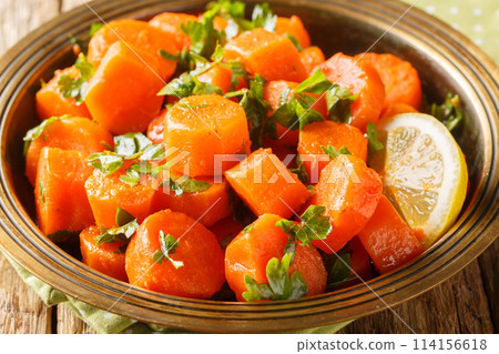 Moroccan cooked carrot salad North African vegan dish with chopped cilantro and dressing of lemon juice and olive oil closeup on the plate. Horizontal Moroccan cooked carrot salad North African vegan dish with chopped cilantro and dressing of lemon juice and olive oil closeup on the plate. Horizontal 114156618