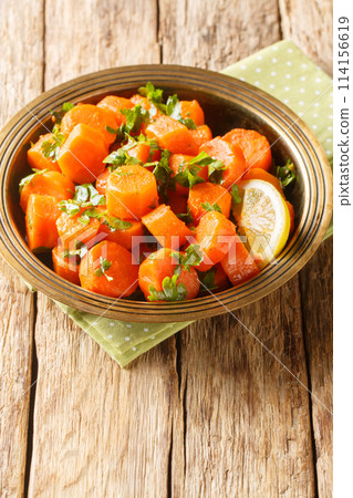 Moroccan carrot salad with cilantro, warm spices, light dressing of lemon juice and olive oil closeup on the plate. Vertical Moroccan carrot salad with cilantro, warm spices, light dressing of lemon juice and olive oil closeup on the plate. Vertical 114156619
