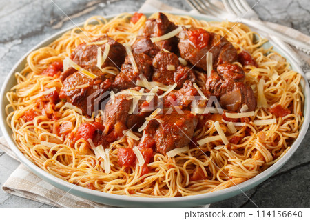 Moshari Kokkinisto or Tas Kebap Greek Veal Stew in a Tomato Sauce with pasta spaghetti closeup on the plate. Horizontal 114156640