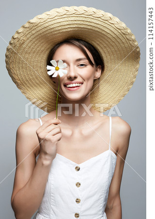 village girl in hat with flower. beautiful smiling young woman with chamomile village girl in hat with flower. beautiful smiling young woman with chamomile 114157443