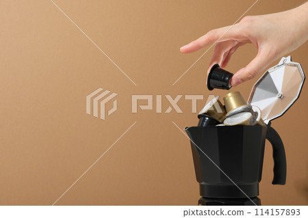 Golden coffee capsules in coffee maker and hand on beige background, space for text Golden coffee capsules in coffee maker and hand on beige background, space for text 114157893