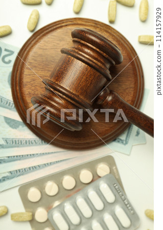 Pills with gavel of justice and money, medical corruption concept. Pills with gavel of justice and money, medical corruption concept. 114157929