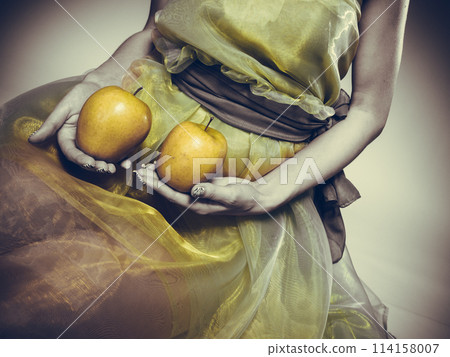 Woman sit in green light dress with apple. Woman sit in green light dress with apple. 114158007