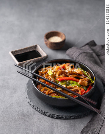 Stir-fry with soba noodles, meat and vegetables on dark background. Asian fast and healthy food. Stir-fry with soba noodles, meat and vegetables on dark background. Asian fast and healthy food. 114158818