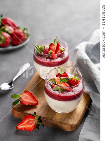 Panna cotta with strawberry and cream in glasses with fresh berries on a wooden board  114158828