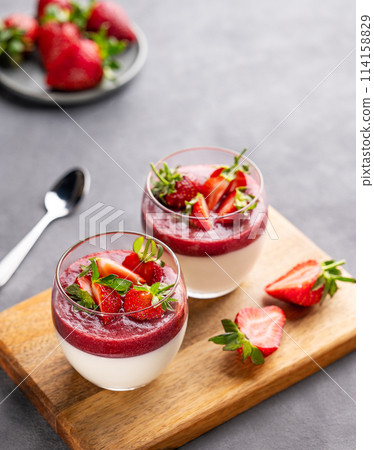 Strawberry and cream panna cotta in glasses with fresh berries on a wooden board  114158829