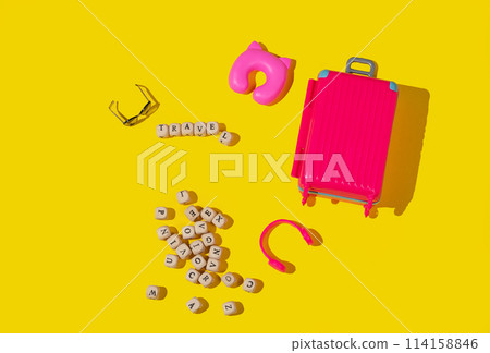 Flat lay pink toy suitcase with travel accessories on a yellow background. 114158846