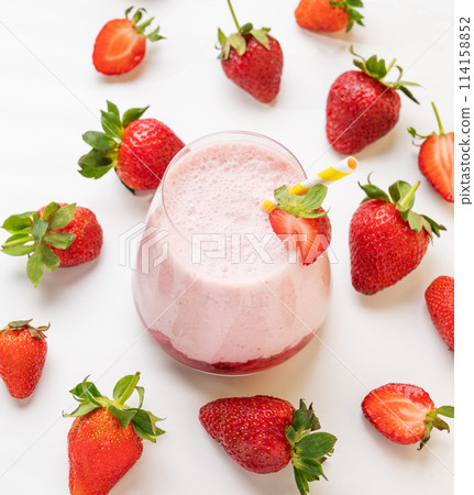 A strawberry milkshake or smoothie in a glass with strawberries on a white background A strawberry milkshake or smoothie in a glass with strawberries on a white background 114158852