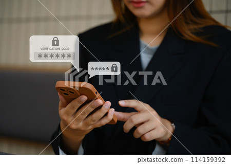 Young businesswoman typing on smartphone entering verification code for login. Cyber security concept 114159392