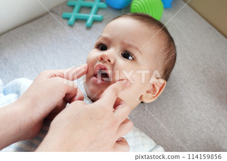 Happy Baby boy lying, mother's hand pressing her cheeks Happy Baby boy lying, mother's hand pressing her cheeks 114159856