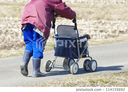 一名農婦乘坐輔助車輛步行到田裡工作。 一名農婦乘坐輔助車輛步行到田裡工作。 114159892