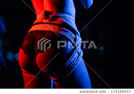 Close-up of a woman's butt tied with ropes using the Japanese shibari technique. Close-up of a woman's butt tied with ropes using the Japanese shibari technique. 114160037