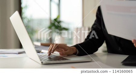 Business woman typing on laptop computer, searching and surfing the internet on office desk Business woman typing on laptop computer, searching and surfing the internet on office desk 114160065