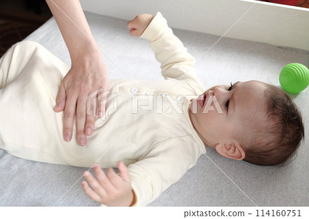 Masseur massaging the tummy of the baby during colic. Mother massaging infant belly, kid laughing 114160751