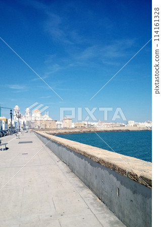 Cadiz embankment panorama with cathedral the Santa Cruz, big breakwater stones and Atlantic ocean. Seafront view of Cadiz. View of the promenade quay Andalusia region, Spain Cadiz embankment panorama with cathedral the Santa Cruz, big breakwater stones and Atlantic ocean. Seafront view of Cadiz. View of the promenade quay Andalusia region, Spain 114161328