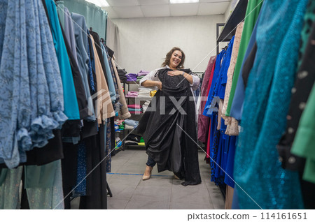 A fat woman chooses clothes in a plus size store.  114161651