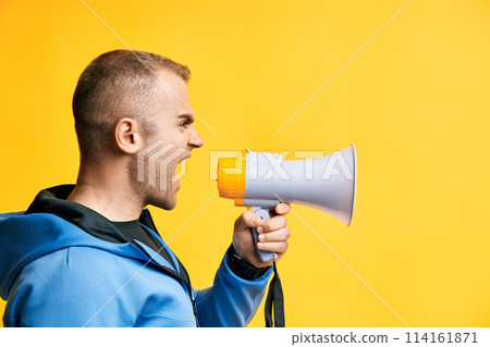 Young angry man shouting and screaming loud holding megaphone Young angry man shouting and screaming loud holding megaphone 114161871