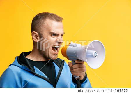Young angry man shouting and screaming loud holding megaphone Young angry man shouting and screaming loud holding megaphone 114161872