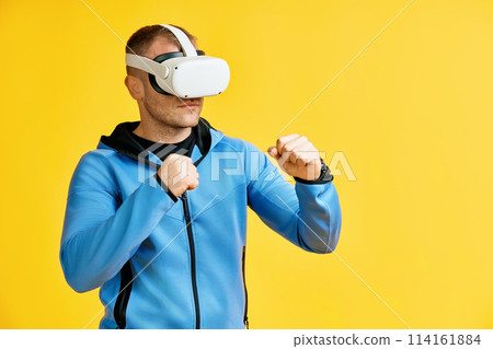 Man wearing virtual reality goggles doing shadow boxing Man wearing virtual reality goggles doing shadow boxing 114161884