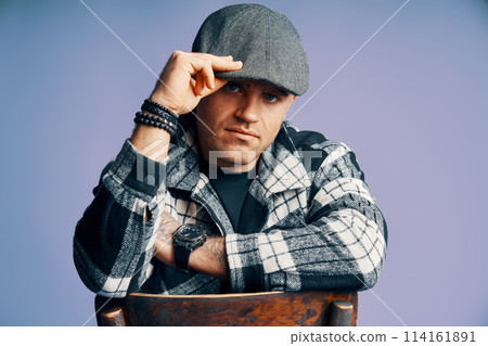 Stylish handsome man posing sitting on the chair on blue studio background Stylish handsome man posing sitting on the chair on blue studio background 114161891