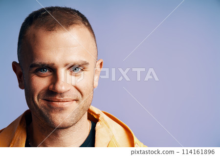 Close-up portrait of handsome young man looking to camera over soft blue background Close-up portrait of handsome young man looking to camera over soft blue background 114161896