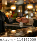 A person is handing a key to a hotel clerk. The scene takes place in a hotel lobby 114162009