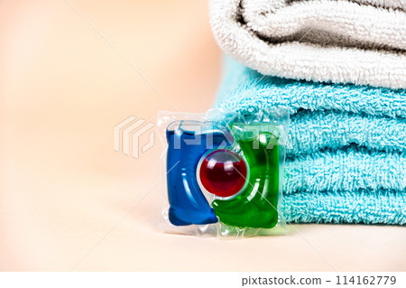 Laundry pod on beige background with soft towels, place for text 114162779