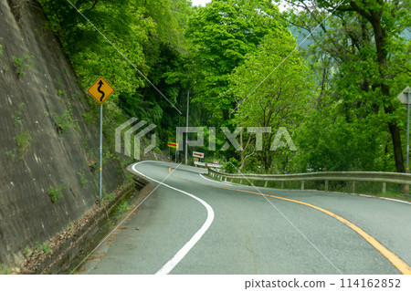 An exaggerated sharp curve on a downhill stretch of national highway An exaggerated sharp curve on a downhill stretch of national highway 114162852