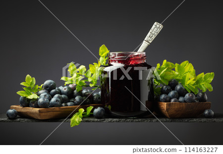 Blueberry jam and fresh berries with leaves. Blueberry jam and fresh berries with leaves. 114163227