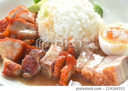 roasted barbecue and crispy pork slice topping plain rice with boiled egg dressing sweet red gravy sauce on plate  114164351