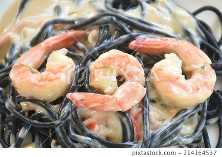 black squid ink spaghetti with shrimp dressing white carbonara cream sauce on plate black squid ink spaghetti with shrimp dressing white carbonara cream sauce on plate 114164537