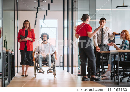 A business leader with her colleague, an African-American businessman who is a disabled person, pass by their colleagues who work in modern offices A business leader with her colleague, an African-American businessman who is a disabled person, pass by their colleagues who work in modern offices 114165180