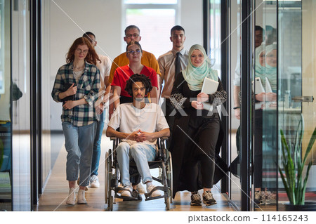 A diverse group of young business people congregates within a modern startup's glass-enclosed office, featuring inclusivity with a person in a wheelchair, an African American young man, and a hijab A diverse group of young business people congregates within a modern startup's glass-enclosed office, featuring inclusivity with a person in a wheelchair, an African American young man, and a hijab 114165243