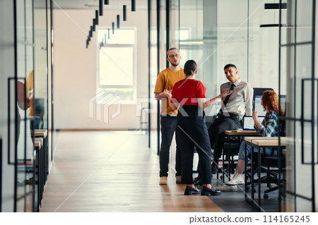 A dynamic group of young entrepreneurs engages in vibrant discussion within a modern glass office space, exploring new business projects and fostering innovation 114165245