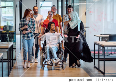 A diverse group of young business people congregates within a modern startup's glass-enclosed office, featuring inclusivity with a person in a wheelchair, an African American young man, and a hijab A diverse group of young business people congregates within a modern startup's glass-enclosed office, featuring inclusivity with a person in a wheelchair, an African American young man, and a hijab 114165525