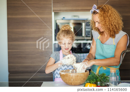 Mother and child daughter girl having fun while making dinner at the kitchen. Mother and child daughter girl having fun while making dinner at the kitchen. 114165600