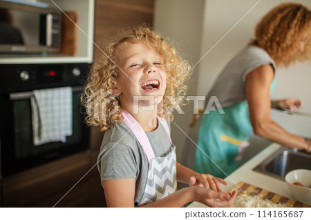 Woman and cute daughter cooking on kitchen, making dough for birthday party. 114165687